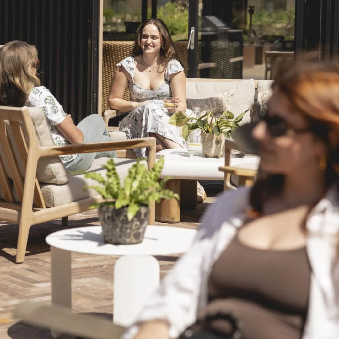 Ladies sat in the sun on wooden garden furniture